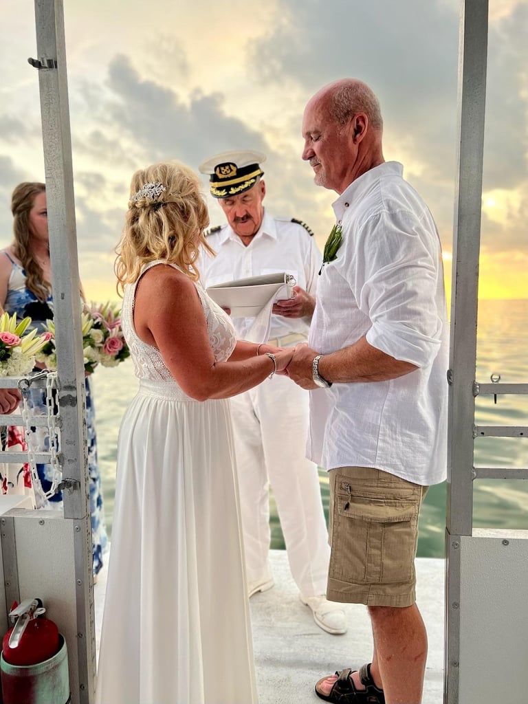 Bride and groom exchange vows during a seaside wedding ceremony with captain officiant and ocean sunset in background